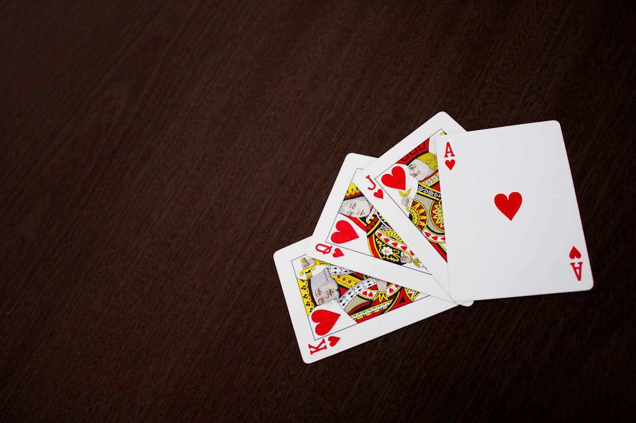 about-bg Elegant flat lay of playing cards featuring ace of hearts on a wooden surface.