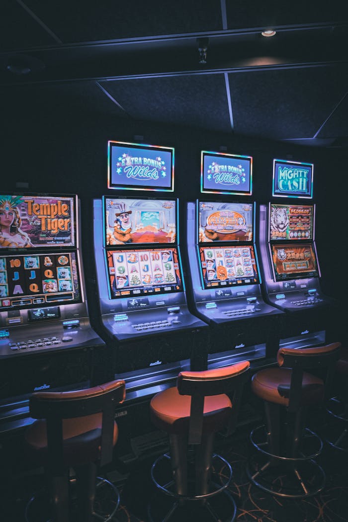 services-02 Row of illuminated slot machines in a dimly lit, empty casino area.