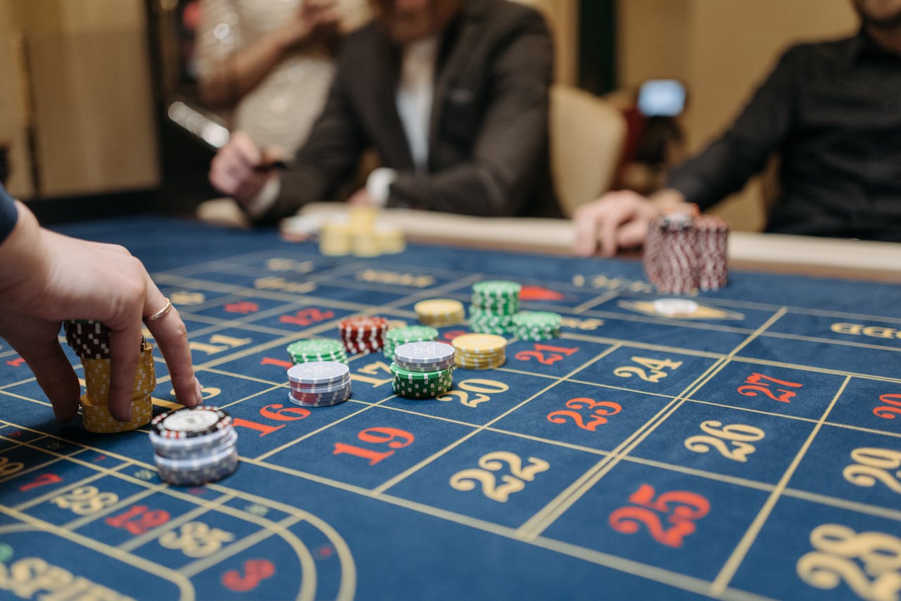 our-story Hands placing betting chips on a roulette table in an upscale casino setting.